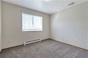 Spare room with baseboard heating and carpet floors