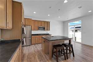 Kitchen with a breakfast bar area, a center island with sink and hardwood / wood-style flooring