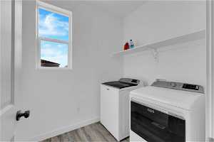 Laundry room featuring washer and dryer and light hardwood / wood-style floors