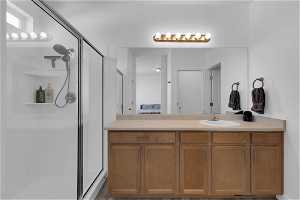 Bathroom with a shower with shower door and vanity with extensive cabinet space