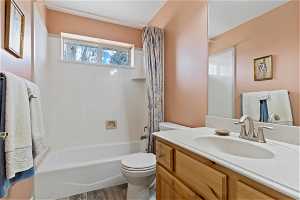 Full bathroom with shower / tub combo, vanity, wood-type flooring, and toilet