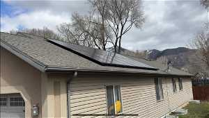 View of home's exterior with solar panels, a garage, and a mountain view