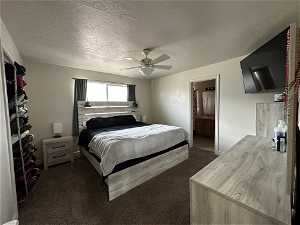 Carpeted bedroom featuring ceiling fan, a textured ceiling, and ensuite bathroom