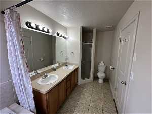 Bathroom featuring dual sinks, oversized vanity, tile floors, toilet, and walk in shower
