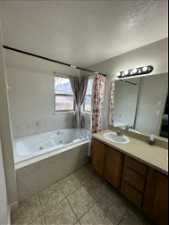 Bathroom with tile flooring, a textured ceiling, and vanity with extensive cabinet space