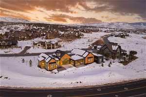 Snowy aerial view featuring back of home and mountain view