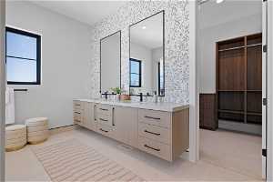 Bathroom with dual sinks, vanity with extensive cabinet space, and plenty of natural light