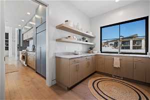Kitchen with sink, high end appliances, and light hardwood / wood-style floors