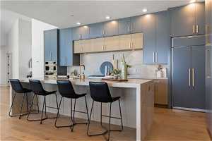Kitchen with a breakfast bar area, light hardwood / wood-style floors, tasteful backsplash, and paneled fridge