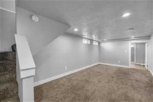 Basement with carpet floors and a textured ceiling