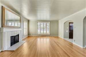 Unfurnished living room featuring a tile fireplace, plenty of natural light, and light hardwood / wood-style floors