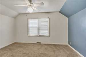 Additional living space with ceiling fan, light carpet, and vaulted ceiling