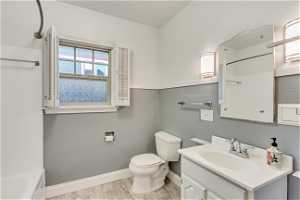 Full bathroom featuring toilet, hardwood / wood-style flooring, washtub / shower combination, tile walls, and vanity