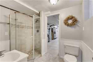 Bathroom with a textured ceiling, toilet, tile floors, and walk in shower