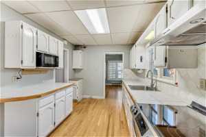 Kitchen featuring white cabinetry, tile countertops, sink, and light hardwood / wood-style floors