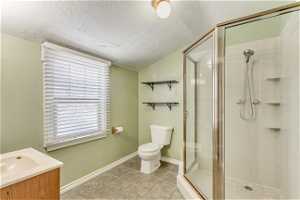 Bathroom with tile flooring, toilet, vanity, and a textured ceiling