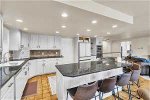 Kitchen featuring sink, a breakfast bar, stainless steel appliances, and white cabinetry