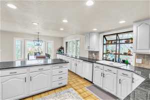 Kitchen featuring white cabinets, backsplash, and pendant lighting