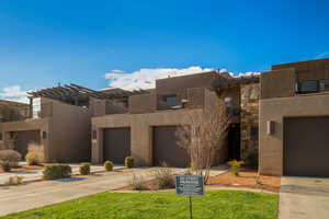 Pueblo-style house featuring a front yard and a garage