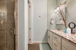 Bathroom with tile floors, a shower with door, and vanity