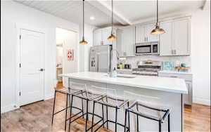 Kitchen with stove, a center island with sink, decorative light fixtures, and a kitchen breakfast bar