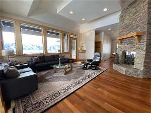Living room with dark hardwood / wood-style flooring and a stone fireplace