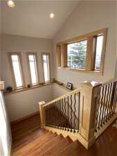 Staircase with a healthy amount of sunlight, hardwood / wood-style flooring, and vaulted ceiling