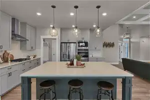 Kitchen featuring light hardwood / wood-style flooring, wall chimney range hood, tasteful backsplash, and stainless steel appliances