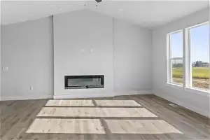 Unfurnished living room with ceiling fan, light wood-type flooring, and vaulted ceiling