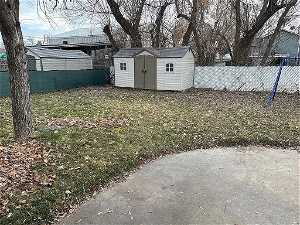 View of fenced back yard with a storage shed & patio