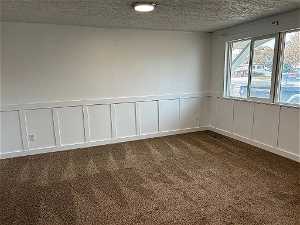 Living/family room with textured ceiling, new carpet, wainscoting, natural light