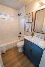 Full bathroom with tiled shower / bath, toilet, vanity, and hardwood / wood-style flooring