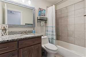 Full bathroom with toilet, shower / bath combo, and vanity