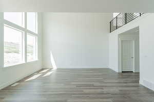 Empty room with hardwood / wood-style flooring and a towering ceiling