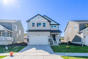 View of front of house featuring a garage, a front lawn, and a porch