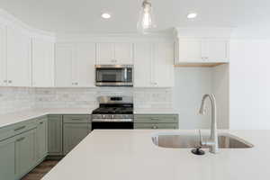 Kitchen featuring decorative backsplash, dark hardwood / wood-style flooring, hanging light fixtures, appliances with stainless steel finishes, and sink