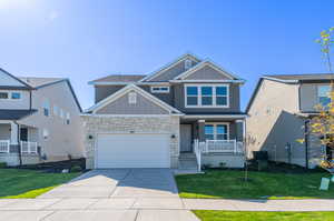 View of front of property featuring a front lawn, a garage, a porch, and central air condition unit