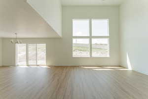 Spare room featuring a notable chandelier, light hardwood / wood-style flooring, and a textured ceiling