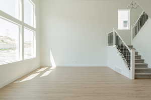 Unfurnished living room featuring light hardwood / wood-style floors, a towering ceiling, and a chandelier