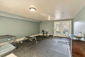 Exercise room featuring french doors, a textured ceiling, and dark carpet