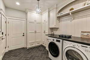 Laundry area featuring dark tile flooring, sink, cabinets, and washer and clothes dryer