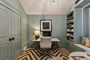 Office with lofted ceiling and light colored carpet