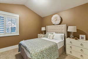 Bedroom featuring lofted ceiling, a textured ceiling, and light colored carpet