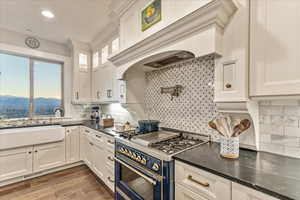 Kitchen featuring backsplash, double oven range, engineered hardwood flooring, and white cabinets