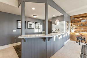 Kitchen featuring a breakfast bar area, kitchen peninsula, light stone counters, and a textured ceiling