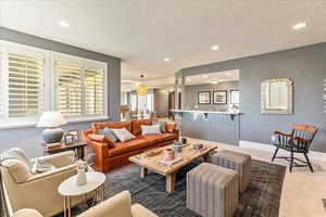 Living room featuring a textured ceiling and dark colored carpet