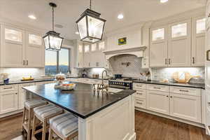 Kitchen with an island with sink, engineered hardwood flooring, a breakfast bar area, tasteful backsplash, and decorative light fixtures