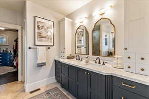 Bathroom featuring engineered hardwood flooring, oversized vanity, and a textured ceiling