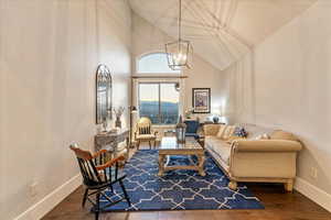 Living room featuring dark wood-type flooring, high vaulted ceiling, a chandelier, and a mountain view