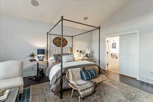 Bedroom with vaulted ceiling, ensuite bath, and engineered hardwood flooring